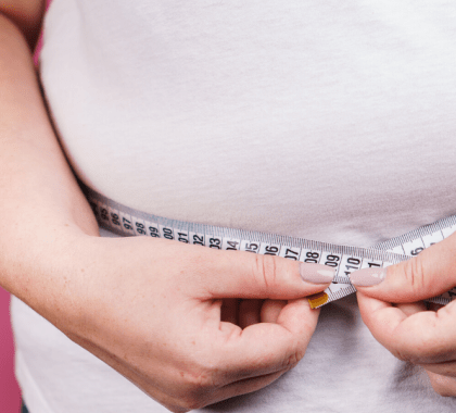 Person measuring stomach with measuring tape