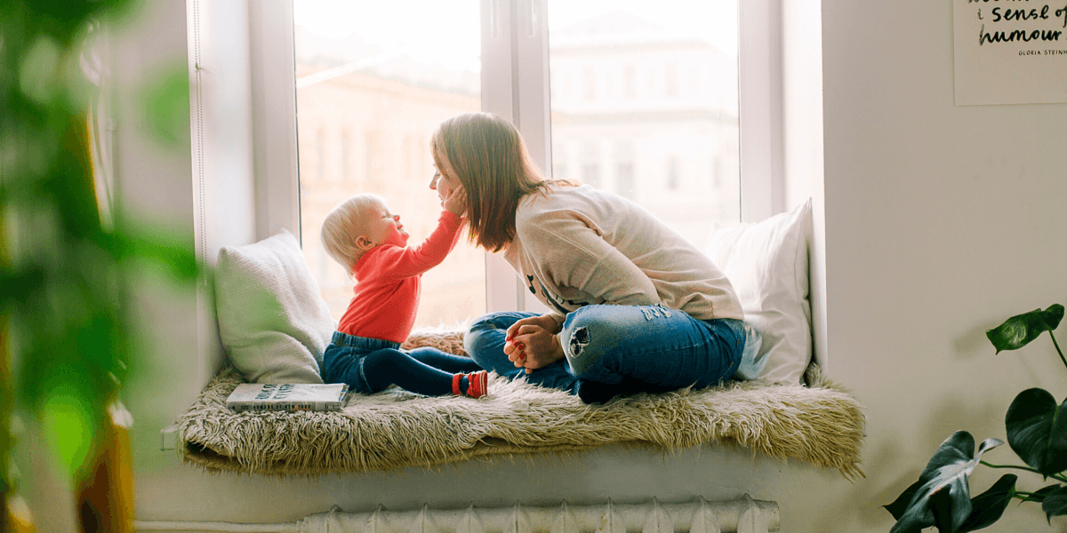 Baby touching mother's face near windowsill