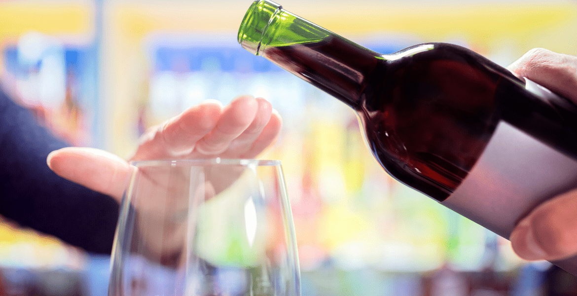 Hand blocking wine being poured into glass