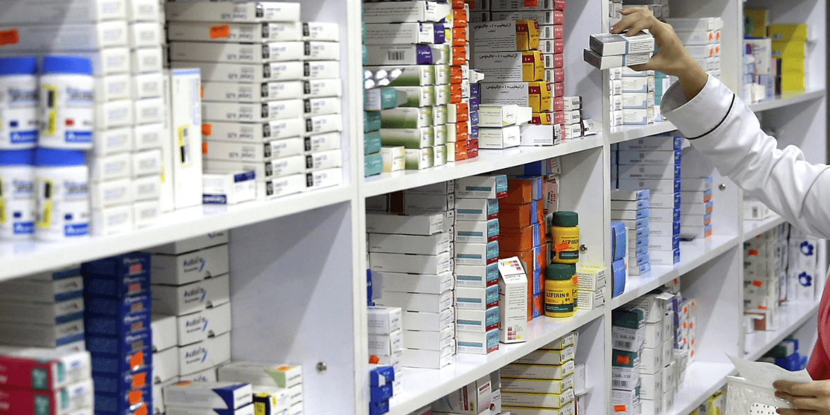 Pharmacist placing boxes of medicine on shelf