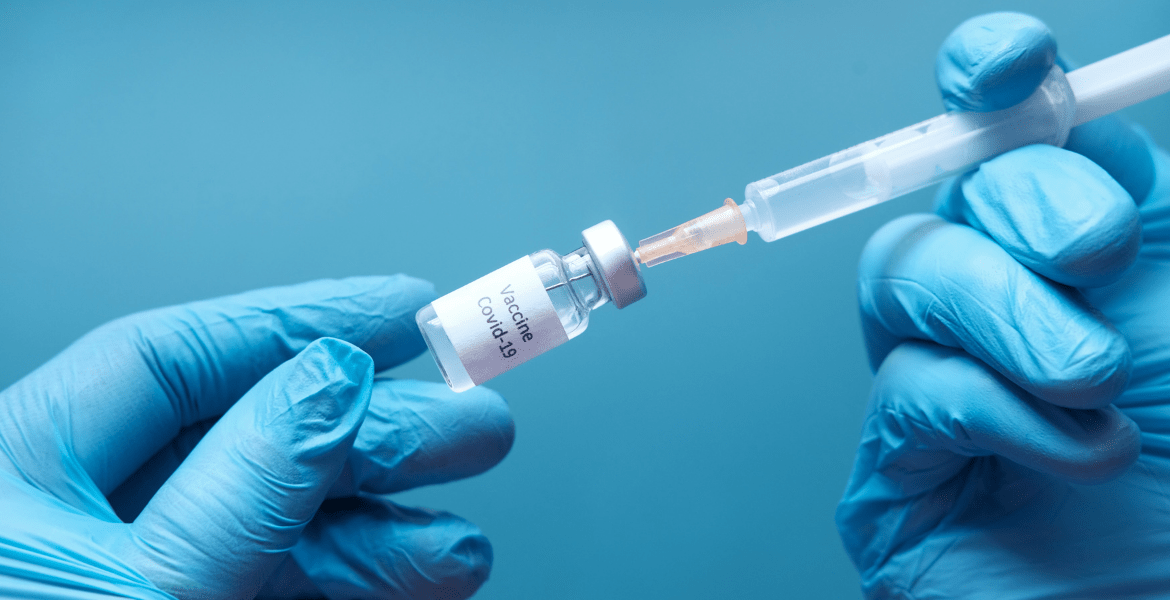 Person holding syringe in vial labelled "Vaccine Covid-19"