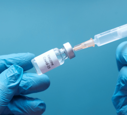 Person holding syringe in vial labelled "Vaccine Covid-19"