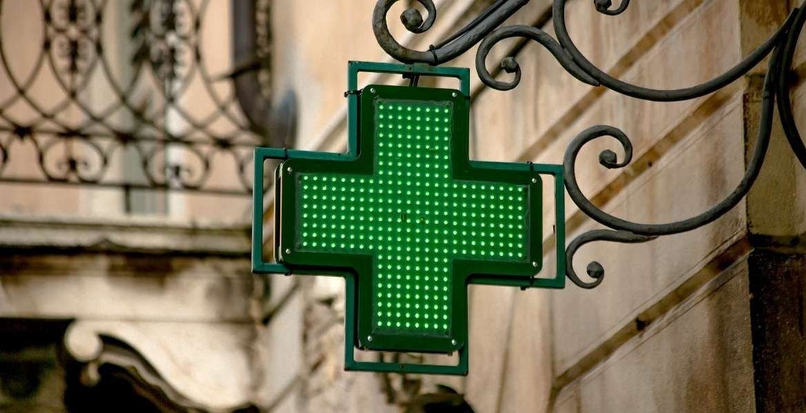 A green cross logo outside a pharmacy