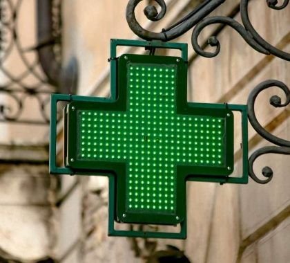 A green cross logo outside a pharmacy