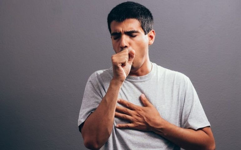 Person coughing while holding chest