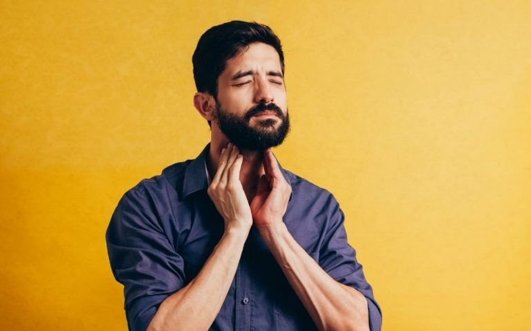 Frowning man clutching throat