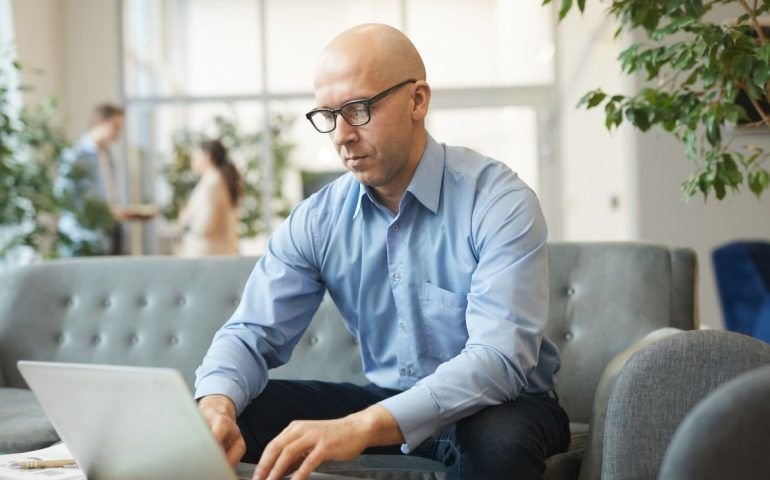 Bald man typing on laptop