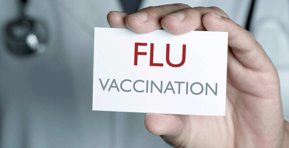 Doctor holding sign saying "FLU VACCINATION"