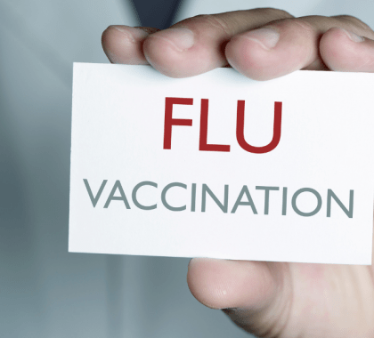 Doctor holding sign saying "FLU VACCINATION"