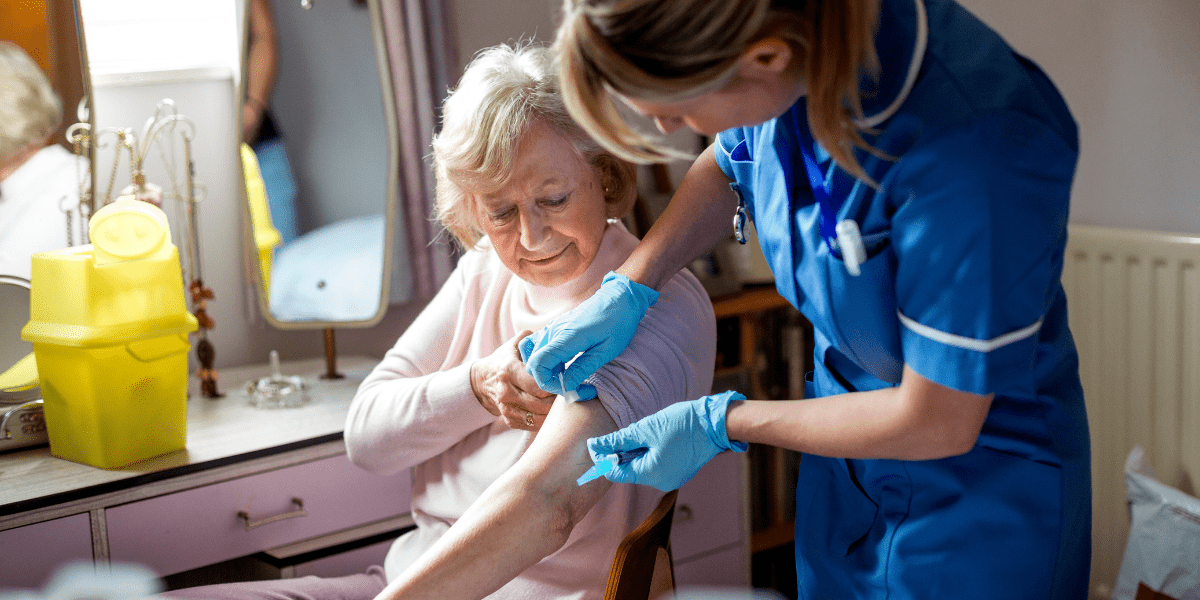 Elderly woman being vaccinated by pharmacist