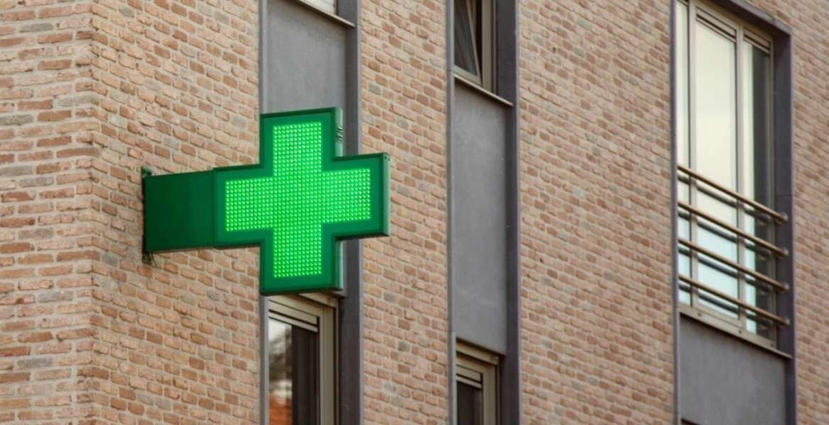 A green cross logo outside a pharmacy