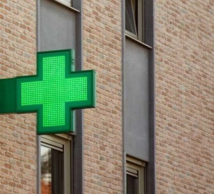 A green cross logo outside a pharmacy