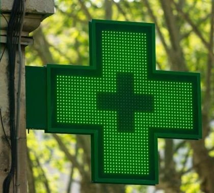 A green cross logo outside a pharmacy