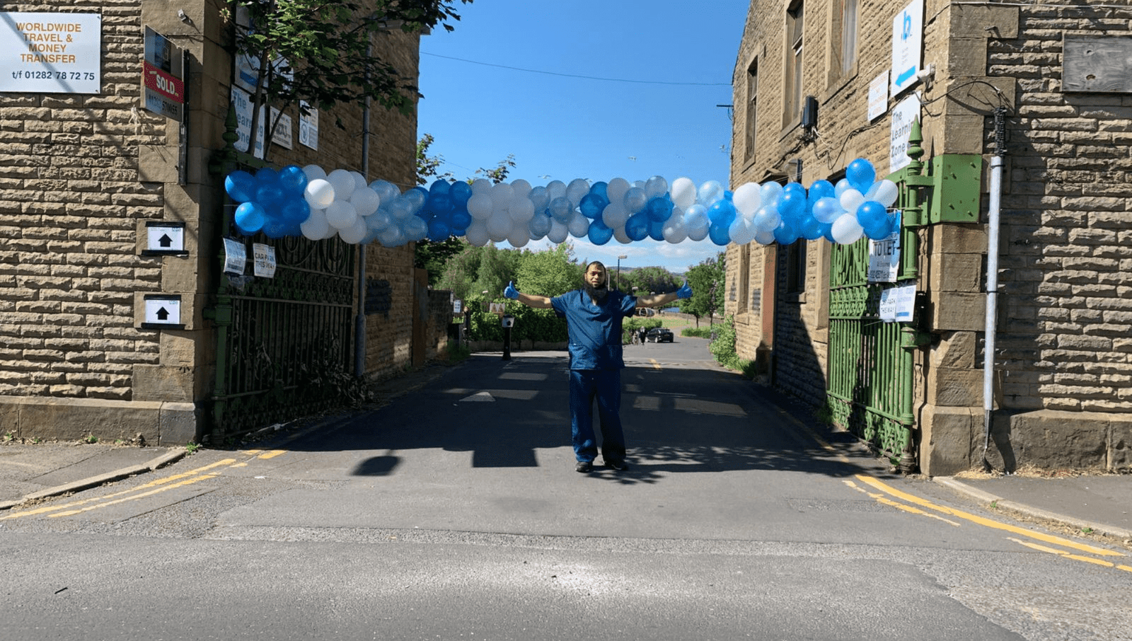 Pharmacist celebrating outside under a banner of balloons