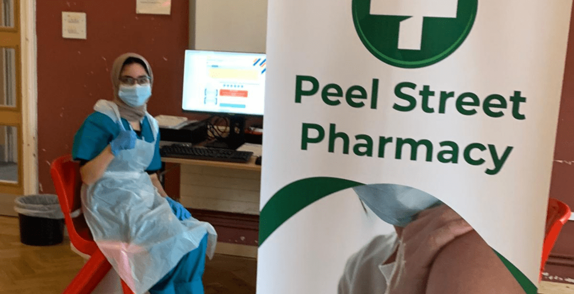 Pharmacist giving thumbs up next to Peel Street Pharmacy sign