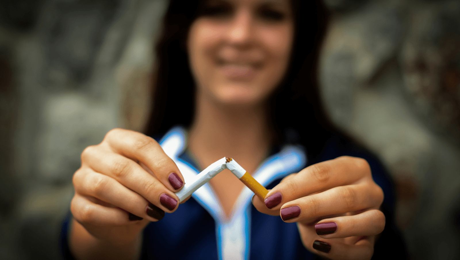 Smiling woman breaking cigarette in half